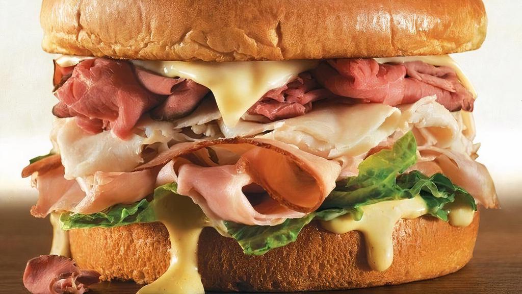 Butcher Block Sandwich · The legend returns…slow roasted beef, smoked turkey and hickory ham piled high on a brioche bun. Topped with Swiss cheese, a blend of honey horseradish sauce and romaine lettuce.