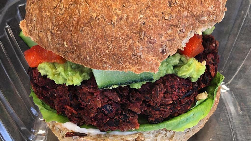Beet Burger · Ground beet, red onion, mushrooms, black beans, rolled oats, walnuts and blend of spices. Topped with  guacamole, cucumber, red bell pepper, red onion and a vegan ranch.