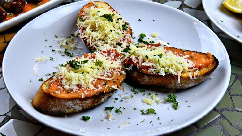 Pan Con Tomate · Toasted baguettes rubbed with tomato, garlic and olive oil puree with manchego cheese. Vegetarian.