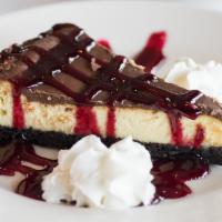 Tarta De Queso · Vanilla cheesecake, chocolate glaze, cookie crust and raspberry sauce.