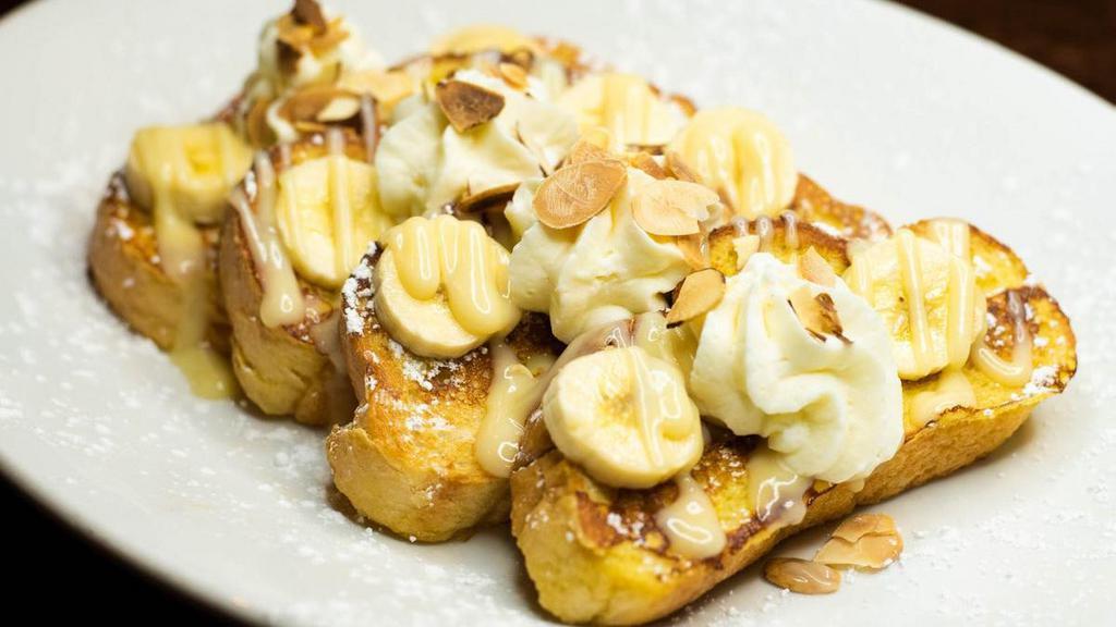 Banana Cream French Toast · 4 slices of vanilla-battered french toast with fresh bananas, whipped cream and toasted almonds, dusted with powdered sugar.