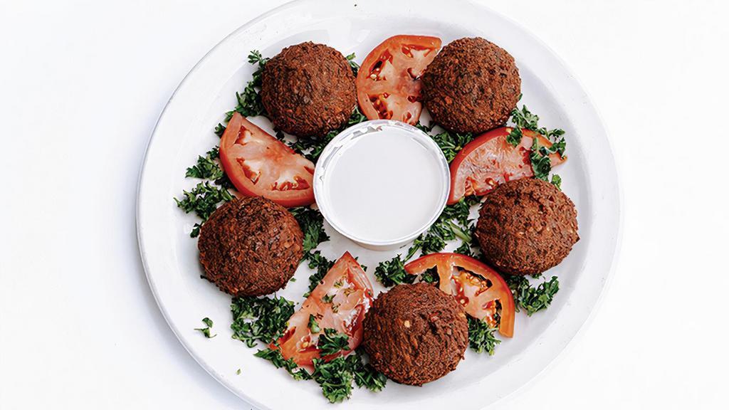 Falafel · Vegan, Gluten-Free, Contains Nuts. Crispy, fried vegan patties made with ground chickpeas, fava beans, onions, and herbs, served with tomato slices and Tahini Lemon dressing