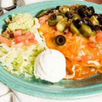 Enchilada Estancia · Soft corn tortillas layered with chicken and pinto beans then topped with your choice of sig...