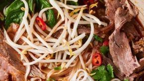 Hue Spicy Noodle Soup · Spicy beef broth noodle soup served with thick rice noodles,
beef brisket, Vietnamese ham, c...
