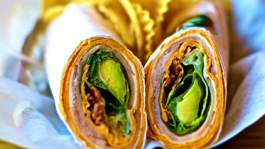 Turkey Avocado Bacon Wrap · Freshly made turkey avocado bacon wrap with a side of chips or fresh fruits. (Pineapple, melon, and grapes). Wrapped in a jalapeño cheddar tortilla wrap. Contains: cream cheese, turkey, bacon, avocado, and romaine lettuce.