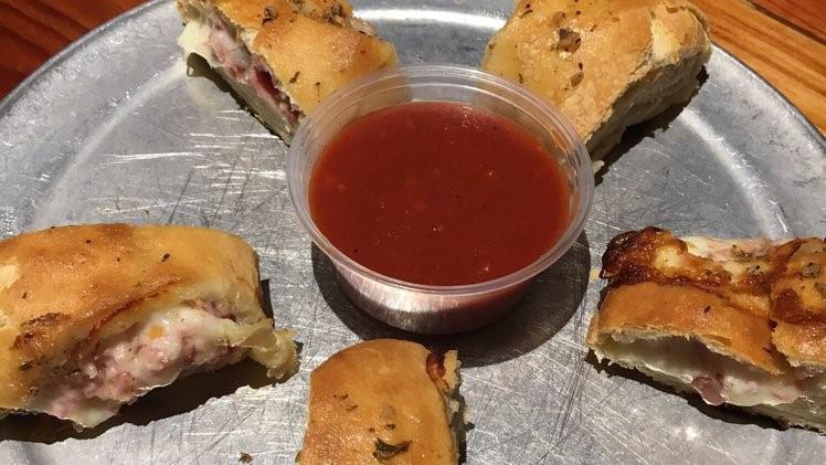 Rollers · Fresh dough rolled out, covered with grated mozzarella cheese and chopped Canadian bacon, then rolled up and baked. Brushed with our olive oil and garlic sauce then sliced into 6 pieces and served with red sauce.