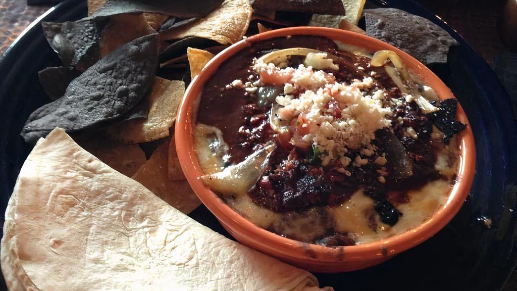 Chorizo Fundido · Rich, flavorful and bold. Warm bean dip with jack cheese, caramelized onion, chorizo sausage, ancho chile sauce, and warm tortillas.