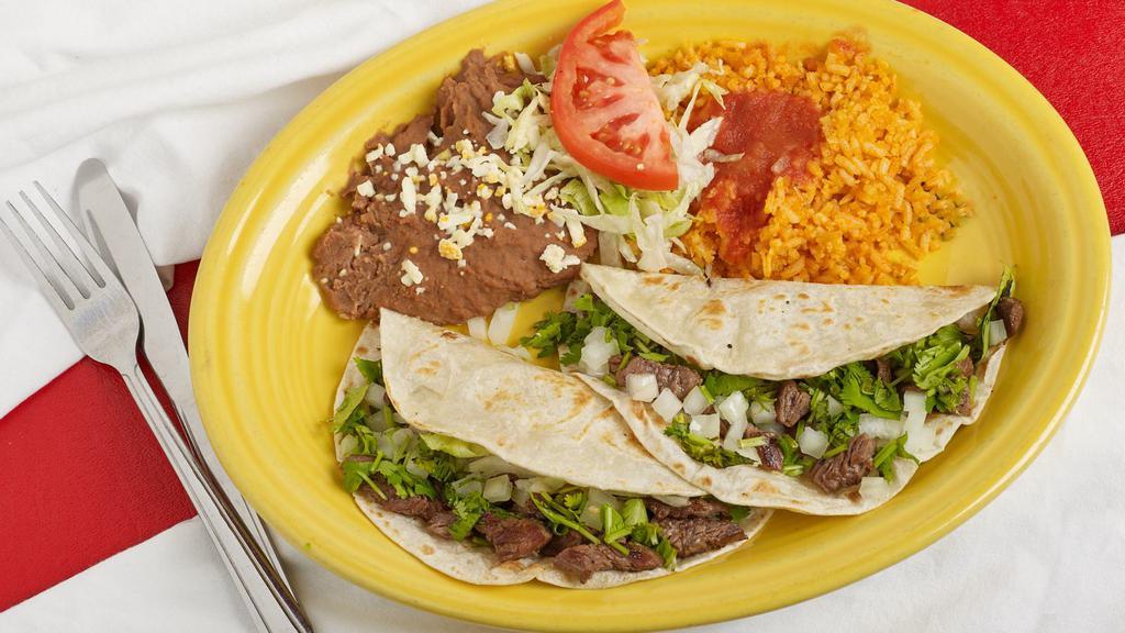 Steak Taco Dinner · Two tacos with sautéed steak topped with lettuce, tomato, and grated Mexican cheese. Served with rice and beans.