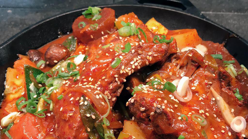 Braised Spicy Pork Ribs · Braised pork ribs cooked with spicy chili sauce (gochujang), daikon radish, potato, onion, zucchini, glass noodle, and scallions. Served with two sides of rice.