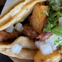Tacos Al Pastor · Three soft corn tacos with strips of pork marinated in our special chile ancho sauce, topped...