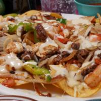 Nachos Texanos · Our tender steak chicken and shrimp cooked with onions, tomatoes and bell peppers.