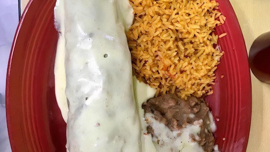 Burrito Texano · Our famous big burrito filled with steak, chicken and shrimp cooked with onions, tomatoes and bell peppers, covered with white cheese sauce and garnish with rice and beans.