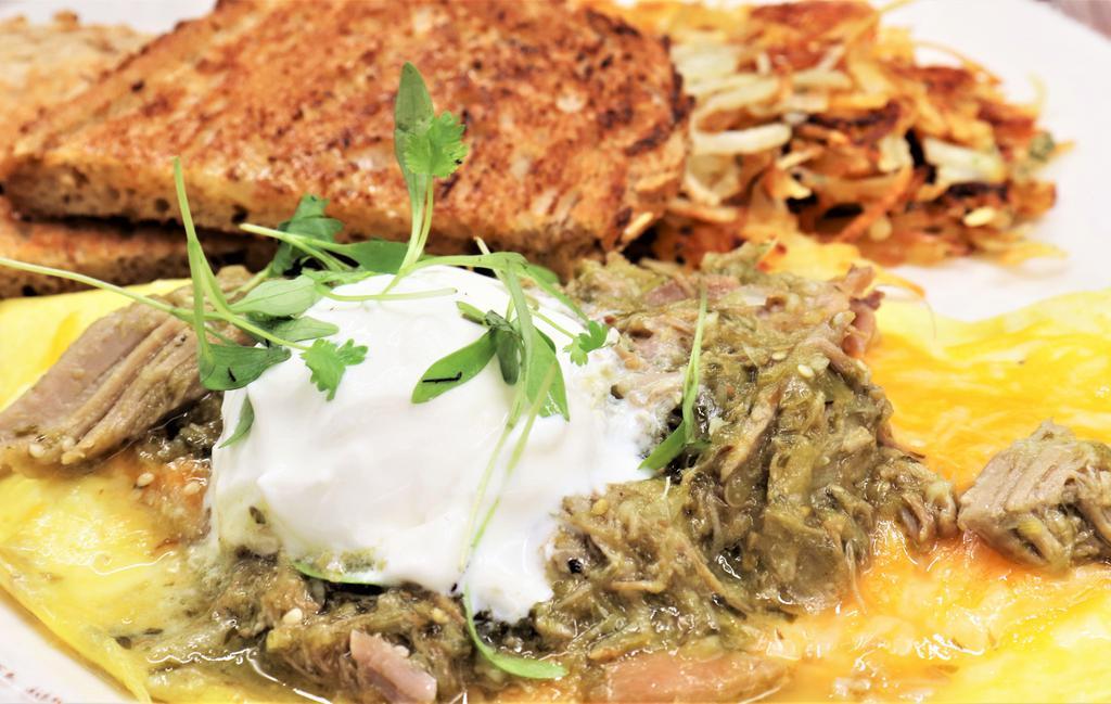Southern Omelet · Slow roasted pork, jalapeno, and onion, smothered in pork green chili. Topped with cheddar-jack cheese, sour cream, and micro cilantro.
