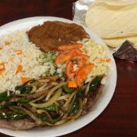 Carne Asada  · Sliced beef grilled on a skillet with onions and green peppers. Served with rice, refried be...