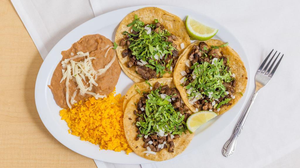 Taco Dinner · Three tacos with cilantro and onion. Rice and beans served on the side.