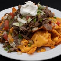 Philly Steak Nachos · Nachos, philly steak, cheddar sauce, onions, green peppers, tomatoes, lettuce, sour cream