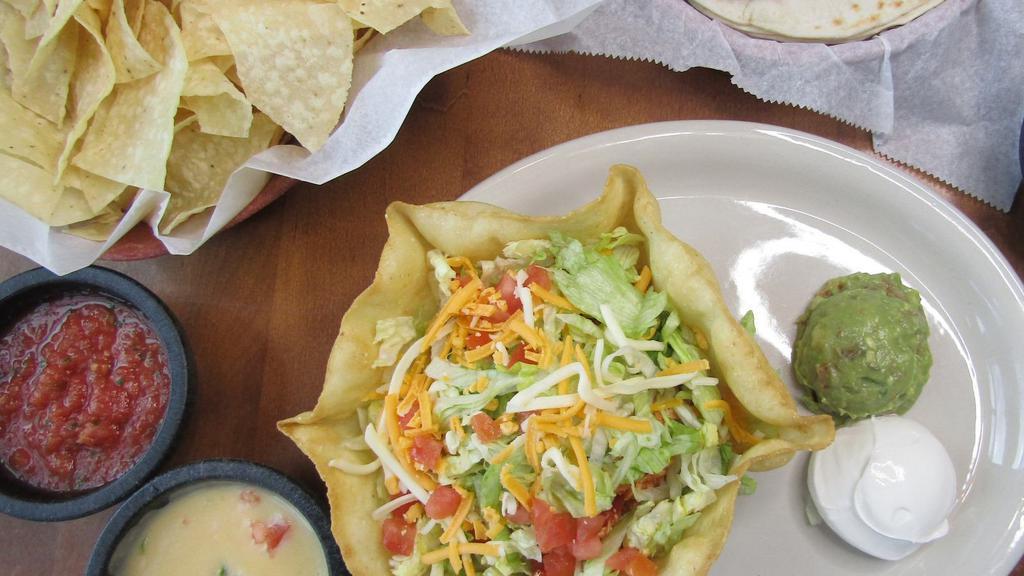 Taco Salad · A crispy flour tortilla shell, generously filled with your choice of meat, beans and rice. Topped with cheddar and jack cheeses, shredded lettuce and diced tomatoes. Served with sour cream and a side of our always-fresh guacamole.