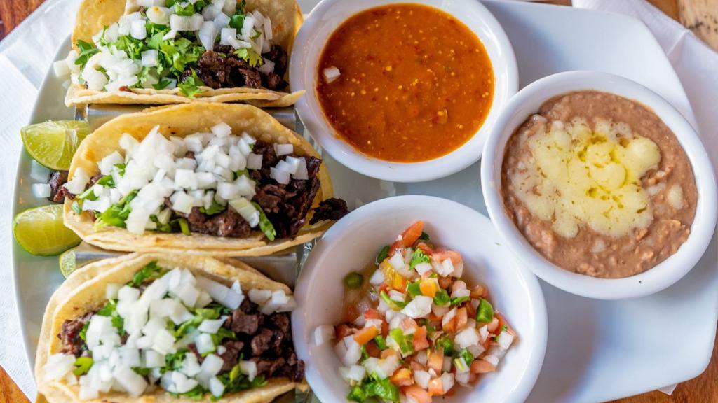 Tacos De Carne Asada · Three flour or corn tortillas stuffed with steak strips. Topped with cilantro and onions. Served with pico de gallo, special sauce and refried beans.