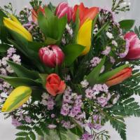Spring Tulips · A dozen mixed tulips designed with mixed greens and wax flower in a beautiful clear glass va...