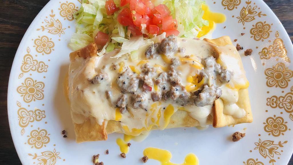 Chimichanga · Two flour tortillas, soft or deep fried, filled with shredded beef or chicken. Topped with lettuce, tomatoes, sour cream, nacho cheese and guacamole, served with rice and beans.