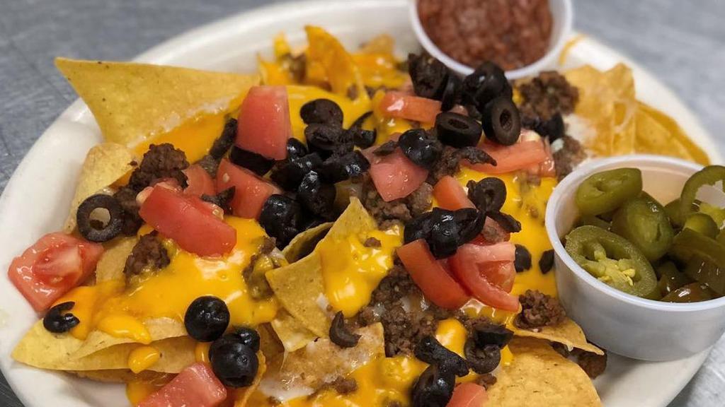 Macho Nachos · Ground beef or chicken, tomatoes, cheese, onions, black olives, jalapenos, sour cream, and salsa.