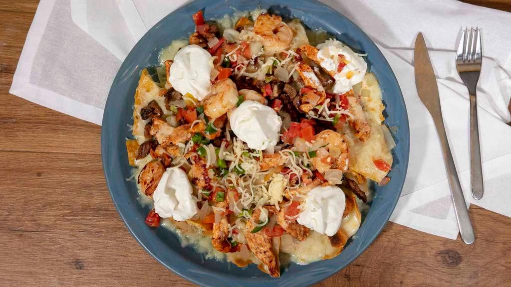 Nachos Al Carbon · A bed of chips with melted cheese, topped with grilled steak, chicken, shrimp, pico de gallo, queso dip and sour cream.