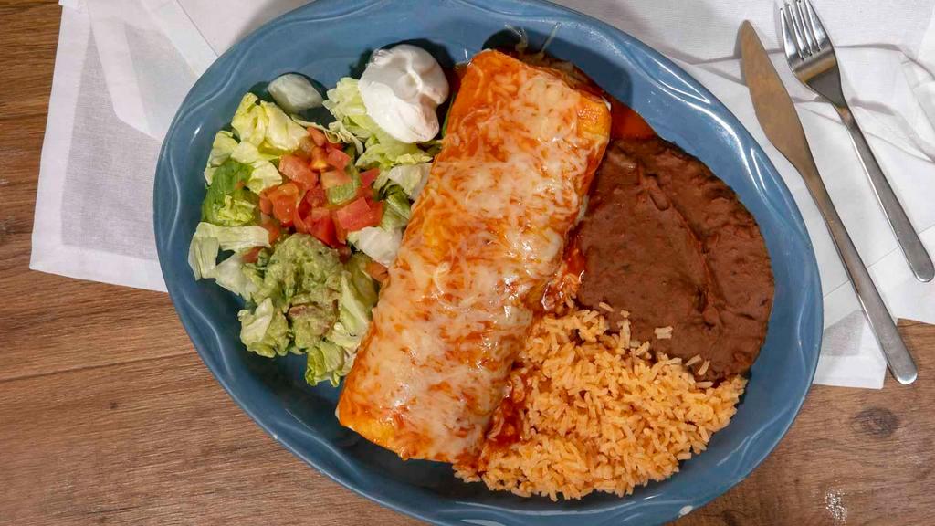 Burrito Suizo · Fully loaded burrito topped with melted cheese red salsa, filled with beans, lettuce, cheese, sour cream, tomatoes. Choice of grilled chicken or steak. Served with rice & beans.