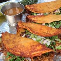 Famous Birria Tacos (4) · El Paso Fave! Red sauce seared corn tortilla tacos with grilled melted queso topped with jui...