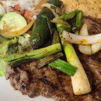 Carne Asada · Grilled steak topped with onions. Served with rice, and choice of charro or refried beans, t...