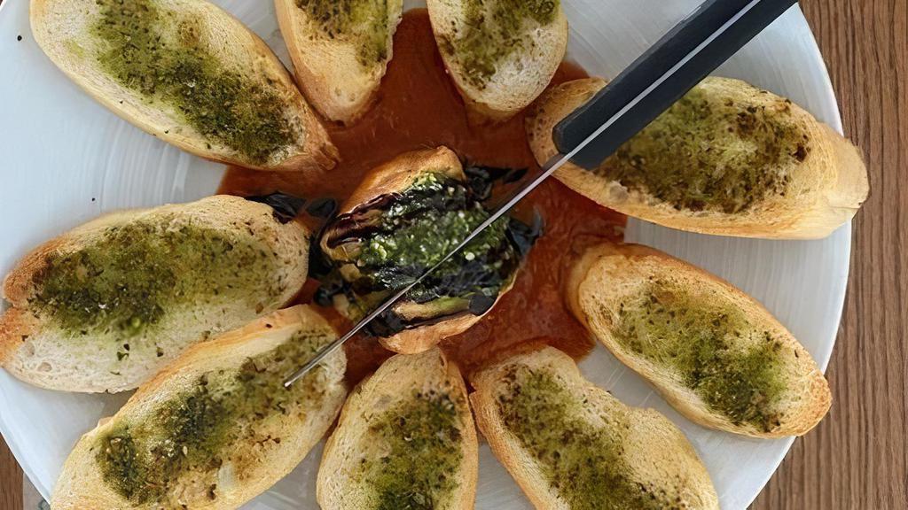 Baked Goat Cheese · Goat cheese coated with crouton crumbs served with french bread basted with pastachio- basil pesto and toasted in wood fired oven. -served with marinara and drizzled with balsamic glaze