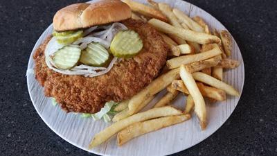 Lunch Pork Tenderloin Sandwich · Fried pork tenderloin topped with fresh lettuce, onion and pickles on a toasted bun, with peppercorn mayo on the side