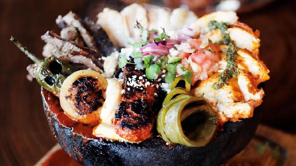Molcajete Mar Y Tierra · Marinated steak, shrimp, chicken breast, chorizo, cotija cheese, cilantro, Mexican red sauce in a molcajete (authentic volcanic rock bowl). Served with rice, re-fried beans, flour tortillas.