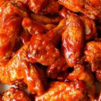 Buffalo Wings · Wings with baffalo sauce in a small bowl.