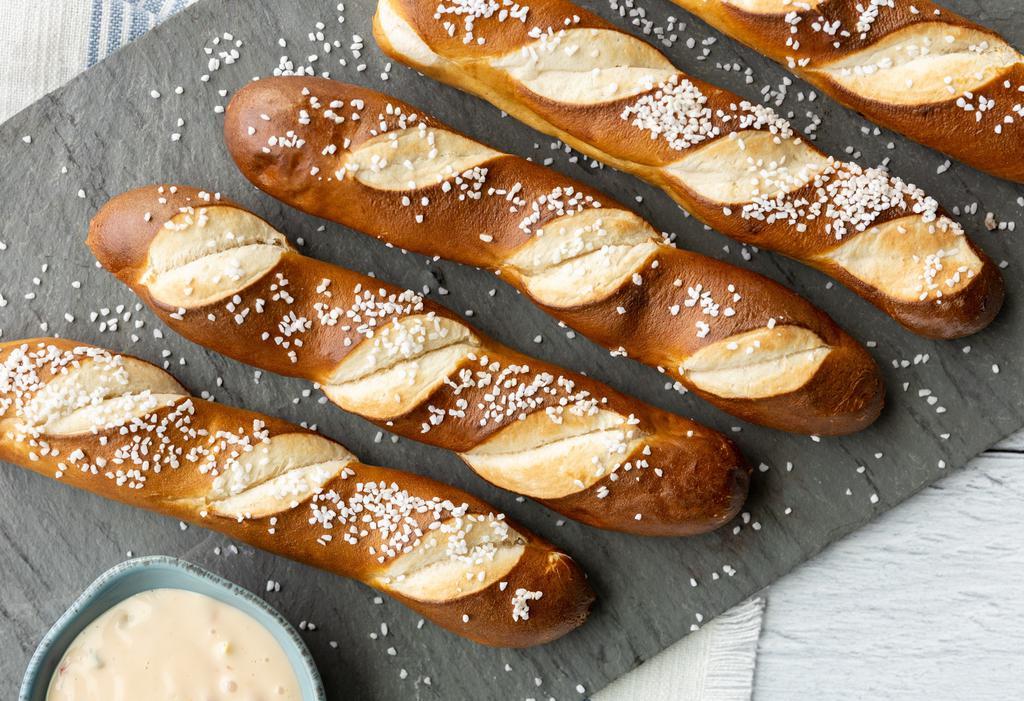 Soft Pretzel Sticks · Warm house-baked pretzels sprinkled with kosher salt & served with white cheddar queso dipping sauce.