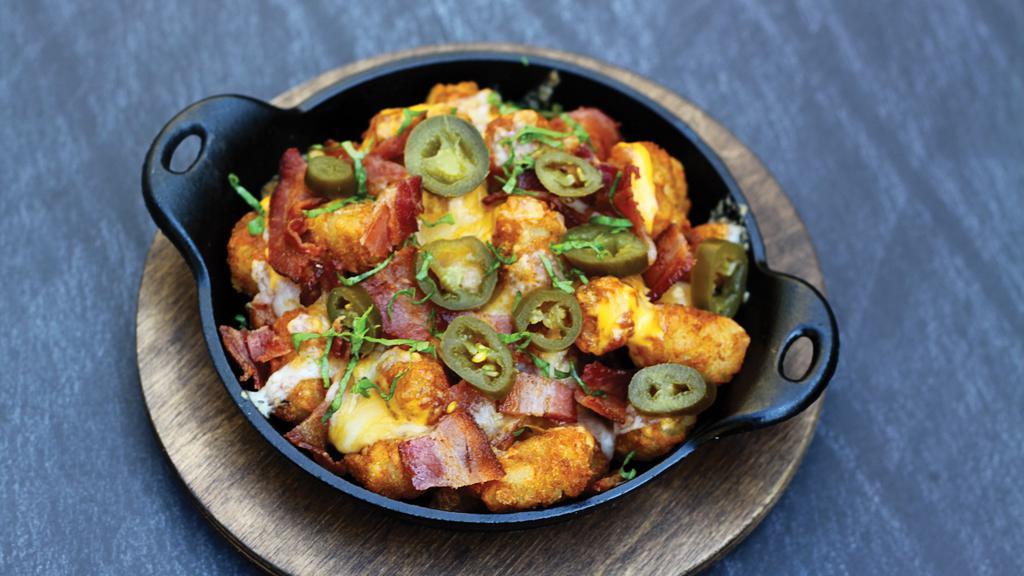 Loaded Tots · Golden tater tots loaded with queso, melted jack & cheddar, crisp bacon bits & fresh jalapeños!