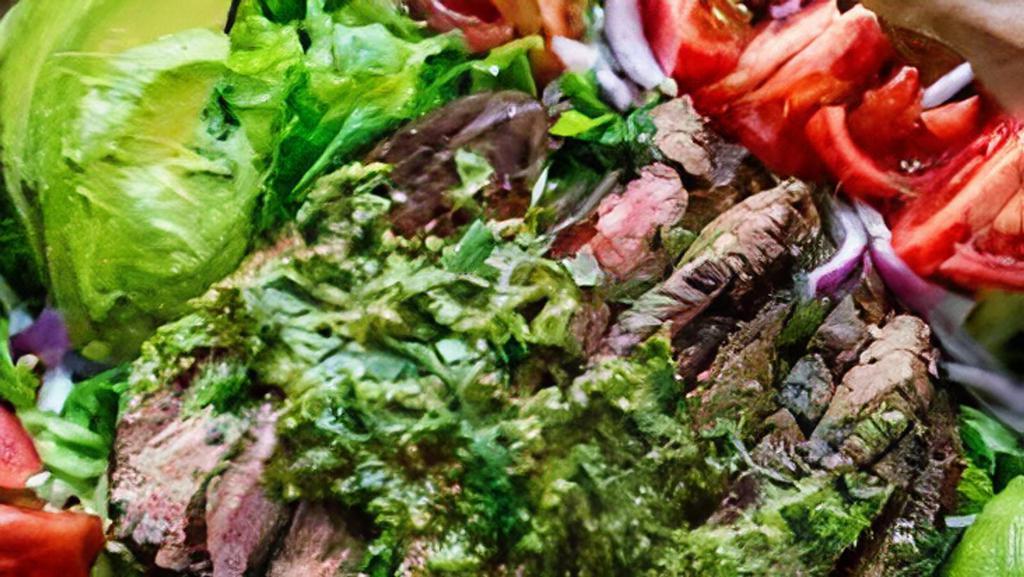 Steak Chimichurri Salad · Spring mix with tender slices of steak rubbed in chimichurri sauce and cooked in olive oil. Garnished with julienne onions, tomato, and avocado.