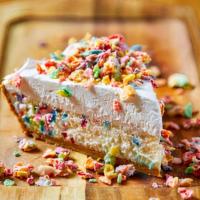 Fruity Pebbles Cheesecake · Funfetti cheesecake in a graham cracker crust topped with whipped cream and glazed fruitty p...