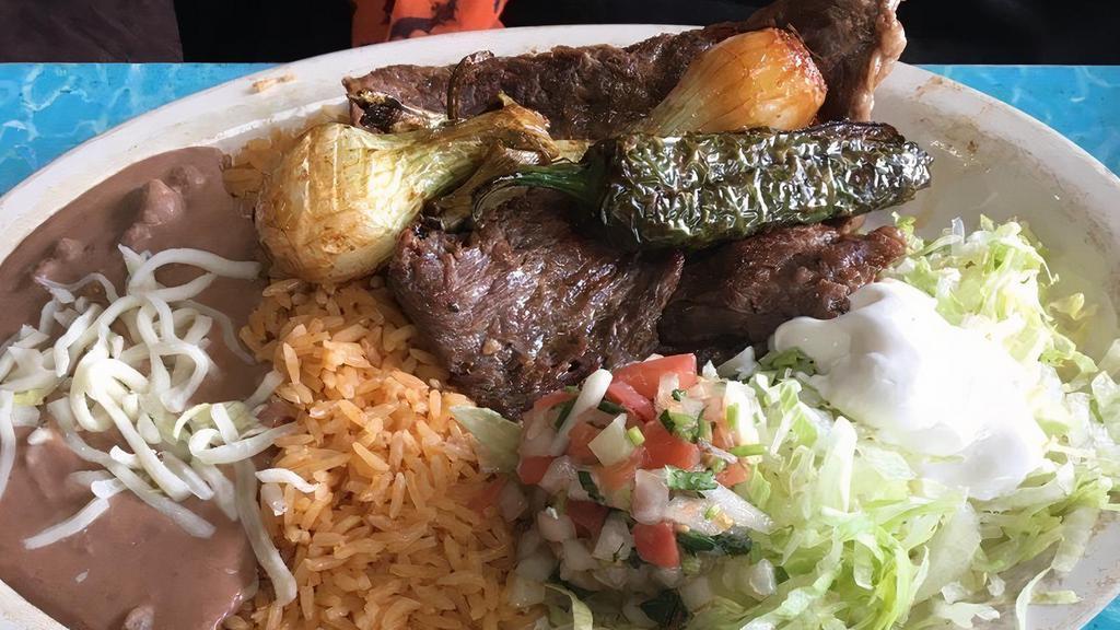 Carne Asada · A succulent grilled beef steak, chile toreado with grilled onions, served with rice, beans, lettuce, pico de gallo, sour cream and tortillas.