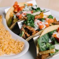 Mexican Cheese Steak Tacos · Three flour shell tacos with grilled steak, onions, and bell peppers topped with queso, lett...