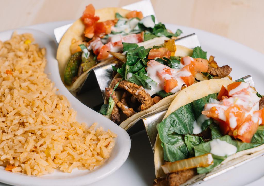 Mexican Cheese Steak Tacos · Three flour shell tacos with grilled steak, onions, and bell peppers topped with queso, lettuce and tomato. Served with Mexican rice.