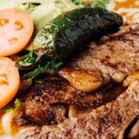 Carne Asada · Tender rib-eye steak served over a bed of grilled onions, served with Mexican rice, refried ...