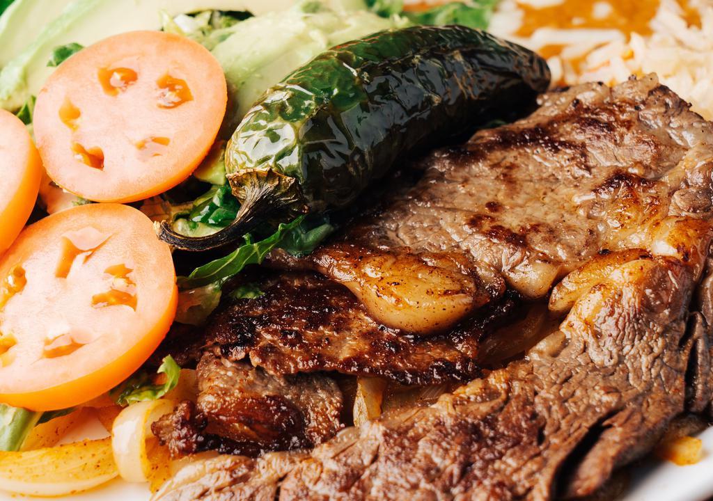 Carne Asada · Tender rib-eye steak served over a bed of grilled onions, served with Mexican rice, refried boons, lettuce, sour cream, pico de gallo and flour tortillas.
