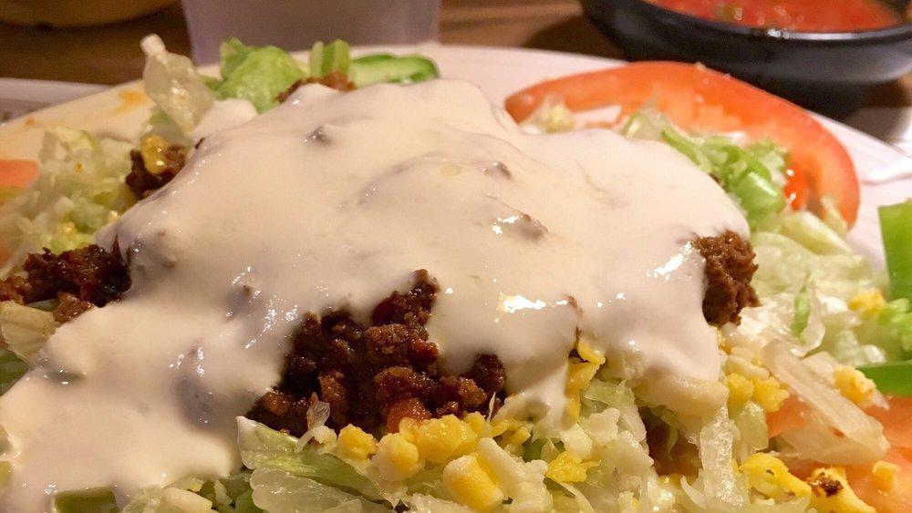 Azteca Plate · Large gordita de masa, handmade ground corn patty fired until golden brown, dipped in chile verde then topped with beans, your choice of meat, a layer of lettuce, cheese, and topped with sour cream.