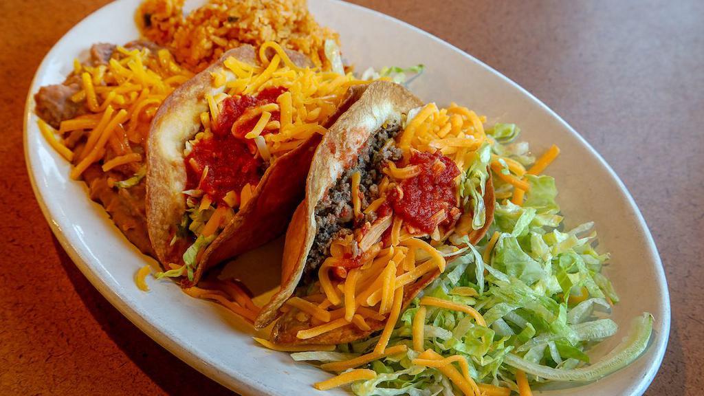Tacos · Traditional! Two flour tortillas filled with ground beef, folded and fried crisp, filled with lettuce and cheese. Served with beans & rice (also available in corn shell or soft flour tortilla)