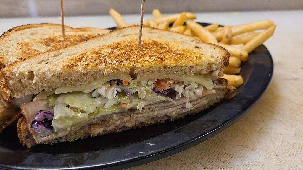 Grilled Turkey Reuben · Deli thin smoked turkey breast, creamy coleslaw, and Swiss cheese piled high on grilled rye bread. Comes with a side of seasoned fries at no additional cost or a different side option for an upcharge.