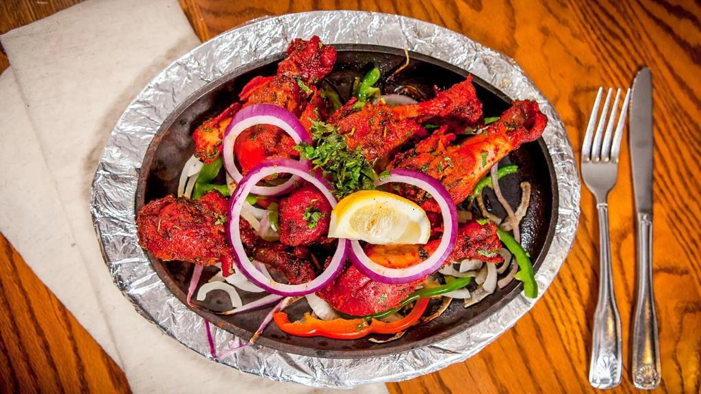 Tandoori Chicken · Chicken marinated in yogurt, ginger garlic paste with special herbs and spices. Cooked on skewer in tandoor (clay oven) with mesquite charcoal served in sizzling plate.