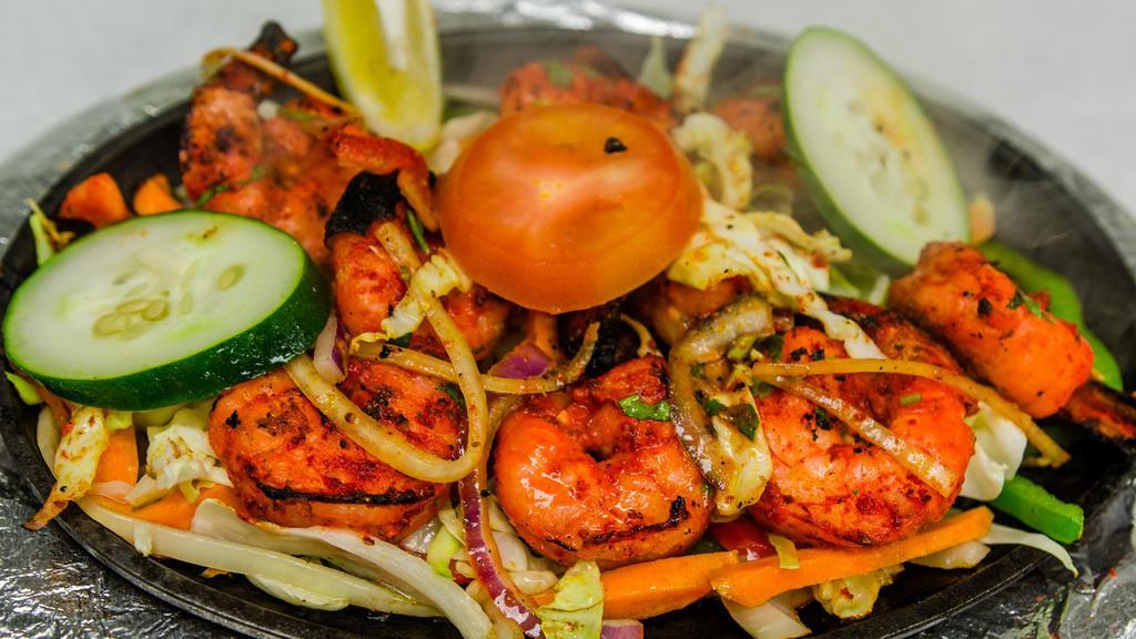 Tandoori Shrimp · Jumbo prawns marinated in yogurt, ginger garlic paste with special herbs and spices. Cooked on skewer in tandoor (clay oven) with mesquite charcoal served in sizzling plate.