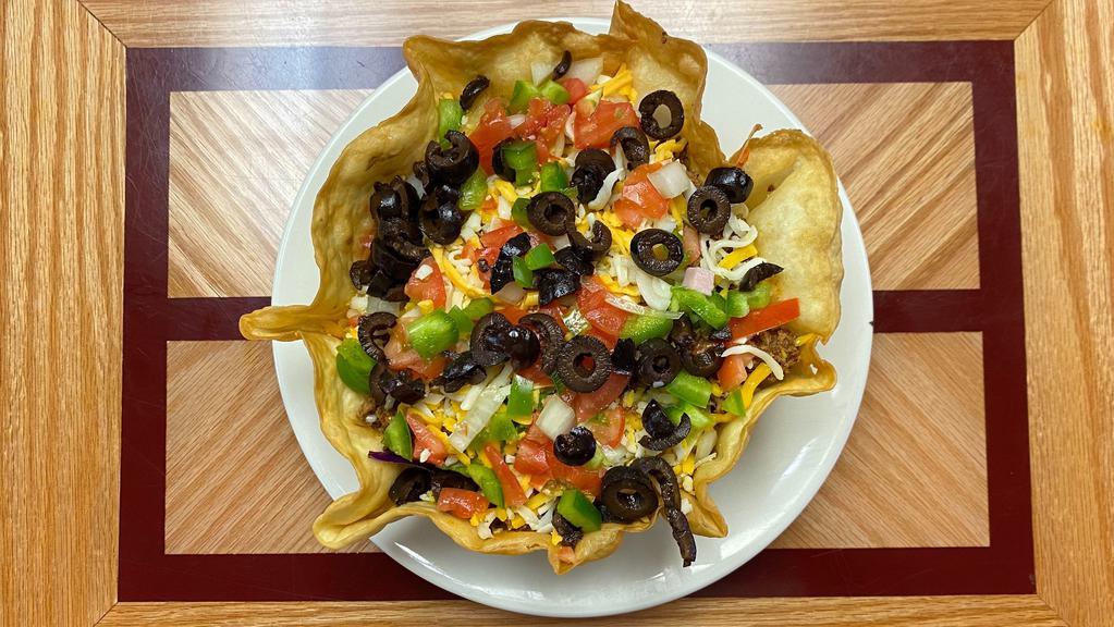 Taco Salad · Spicy ground beef, black olives, onions, tomatoes, Cheddar cheese, over fresh greens in a crispy tortilla bowl, served with sour cream and salsa.