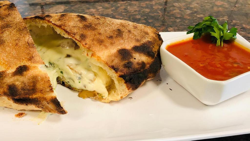 Spinach & Mushroom Calzone · Sautéed spinach & mushrooms, with ricotta & mozzarella cheese hand wrapped into a calzone and then baked in our wood fired oven.  Served with a side of our red sauce.
