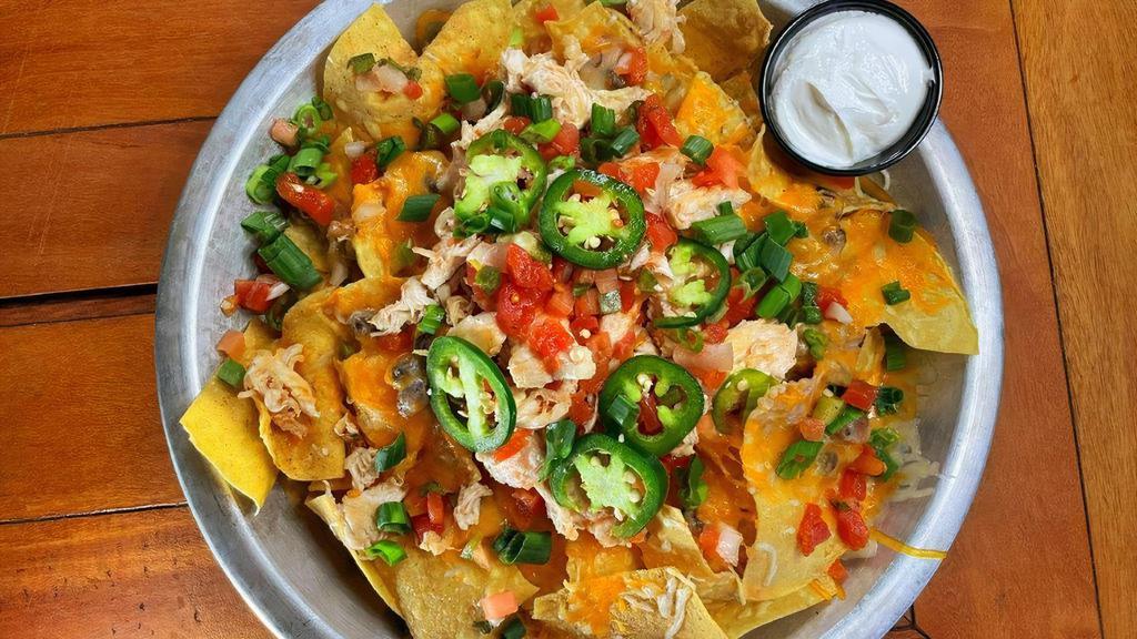 Chicken Nachos · Crisp tortilla chips smothered with our black bean dip, fresh salsa, jalapeños and melted cheese. Topped with grilled chicken and a side of sour cream.